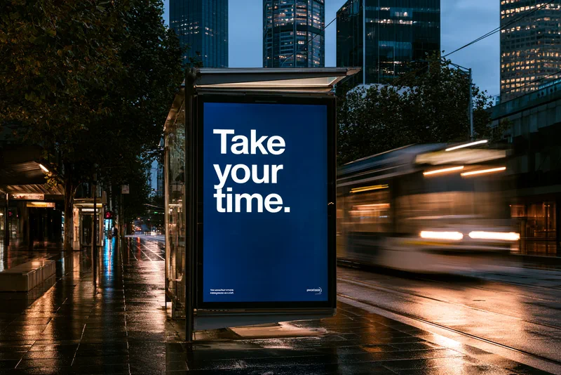 A Kinder Voice — a tram shelter poster at night reading Take your time. in white on blue, a tram passing in a blur of light